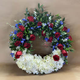 Circular floral wreath with red roses, white flowers, and blue accents