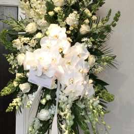 Tall white floral standing spray with orchids and roses on an easel