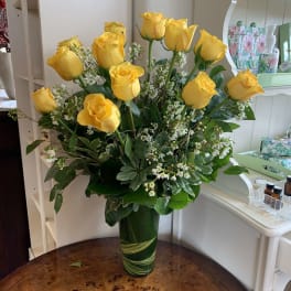 Yellow roses arranged in a tall green glass vase