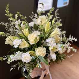 Cream roses and white lilies in a woven basket arrangement