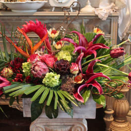 Tropical floral arrangement with pink lilies and protea in a rectangular container