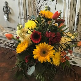 Bright mixed bouquet with sunflowers, tulips, and red blooms in a glass vase