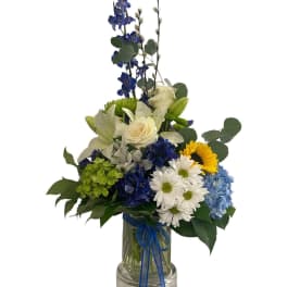 Blue and white floral arrangement in a glass vase with a ribbon