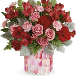 Pink and red flower arrangement in a patterned vase