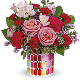 Pink and red mixed flower bouquet in a colorful mosaic vase