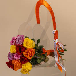 Bouquet of multicolored roses in a clear gift bag with orange ribbon