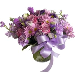 Lavender and pink bouquet in a glass vase with a purple ribbon