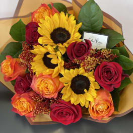 Bouquet of sunflowers and red-orange roses wrapped in brown paper