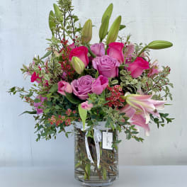 Pink roses and lilies arranged in a clear glass vase