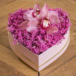 Heart-shaped pink flower box filled with pink orchids and tiny blossoms