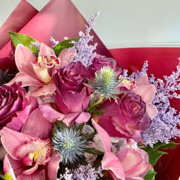 Pink orchid and rose bouquet with lavender filler in red wrap