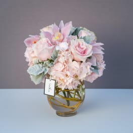 Pink roses and orchids arranged in a glass vase