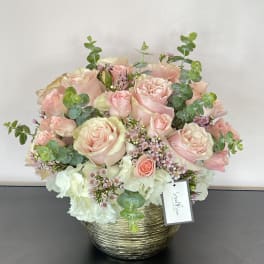 Pink and white rose bouquet in a gold basket vase