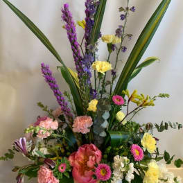 Mixed floral arrangement in a wooden box with tall purple spikes and pink blooms