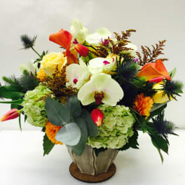 Mixed bouquet with orchids, roses, hydrangeas, and orange calla lilies in a metal vase