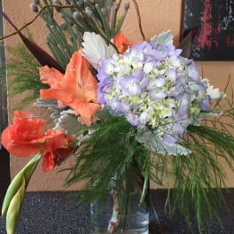 Bouquet of lavender hydrangea and orange lilies in a glass vase