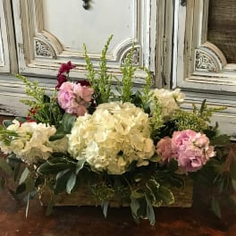 Low floral arrangement with white and pink blooms in a rectangular container