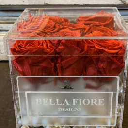 Red roses in a clear acrylic box with pearl accents