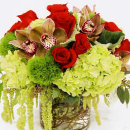 Bouquet of red roses, green hydrangeas, and orchids in a glass vase