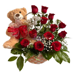 Red roses in a basket with a teddy bear and ribbon