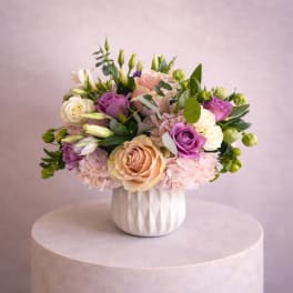 Bouquet of pink, purple, and white roses in a white vase