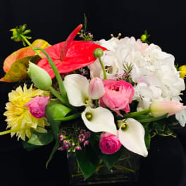 Mixed bouquet with white hydrangea, pink anthurium, and calla lilies in a glass vase