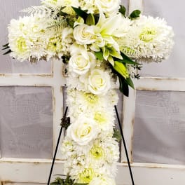 White floral cross on a stand with roses and chrysanthemums