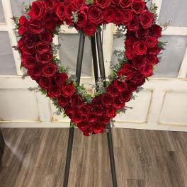Heart-shaped red rose wreath on a black easel