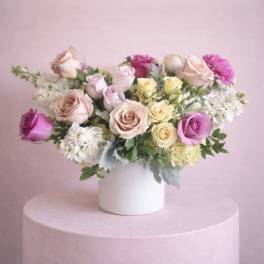 Mixed roses in a white vase on a pink pedestal