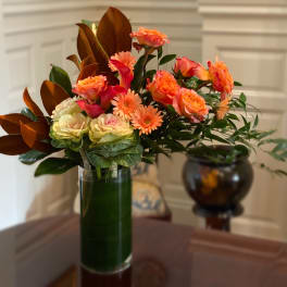 Orange and pink mixed bouquet in a tall glass vase