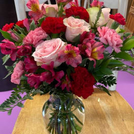 Mixed bouquet of pink and red flowers in a clear glass vase