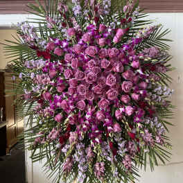 Large standing spray of pink roses and purple orchids with palm fronds