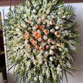 Large standing spray of white and peach roses with white blooms and palm fronds