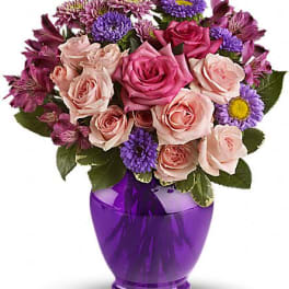 Pink and purple mixed bouquet in a purple glass vase