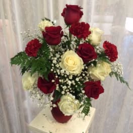 Red and white roses arranged in a vase with baby's breath
