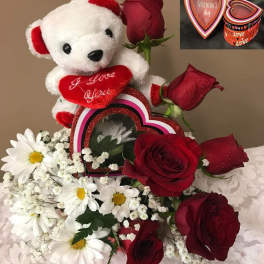 Teddy bear with red roses and white daisies in a Valentine gift arrangement