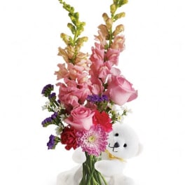 Pink and red flower arrangement with a white teddy bear