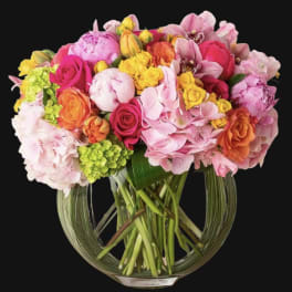 Mixed bouquet of pink, yellow, and orange flowers in a glass vase
