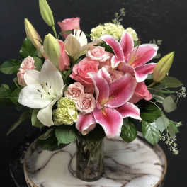 Pink lilies and roses arranged in a glass vase