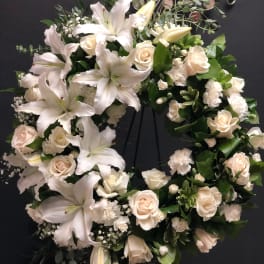 White lily and rose wreath on a dark stand