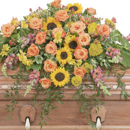 Casket spray with peach roses and yellow sunflowers