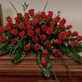Large arrangement of red roses on a wooden casket