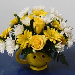 Yellow roses and white daisies in a smiley-face mug