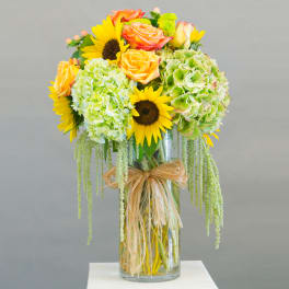 Bouquet of sunflowers, roses, and green hydrangeas in a glass vase