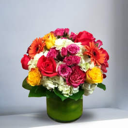 Mixed bouquet of roses, gerbera daisies, and hydrangeas in a green vase