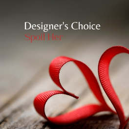 Red ribbon curled into a heart shape on weathered wood with text reading Designer's Choice Spoil Her