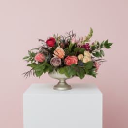 Mixed pink and peach rose arrangement in a silver pedestal bowl