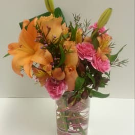Orange lilies and pink carnations in a clear glass vase
