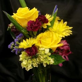 Yellow roses and mixed flowers in a glass vase