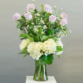 Lavender roses and white hydrangeas in a clear glass vase